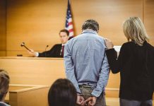 Man handcuffed in courtroom with supportive woman present