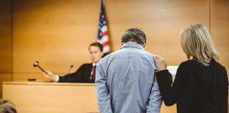 Man handcuffed in courtroom with supportive woman present