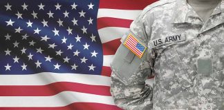 US soldier in camouflage uniform with American flag