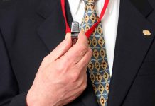 Person holding a whistle on a red lanyard.