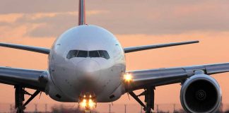 Airplane on runway during sunset, lights on.