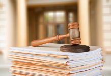 Gavel resting on stack of paperwork in courtroom.