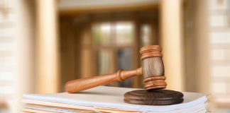 Gavel resting on stack of paperwork in courtroom.