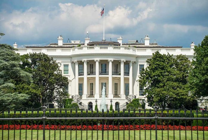 White building with columns behind a black fence.