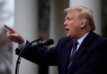 Man gesturing while speaking at a podium outside