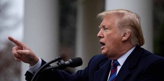 Man gesturing while speaking at a podium outside