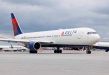 Delta Airlines airplane on airport runway, cloudy sky.