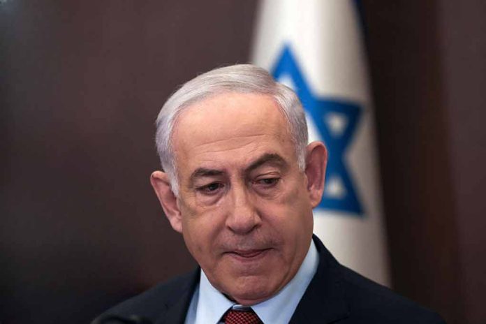 Man in suit with Israeli flag in background.