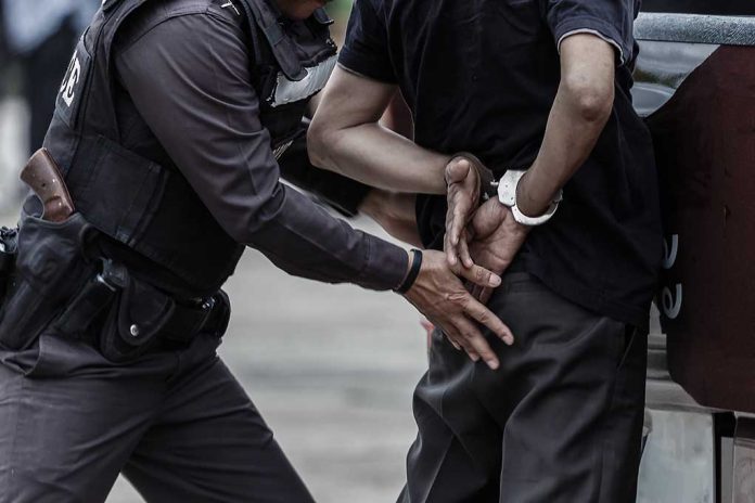 Police arresting person against a wall outdoors