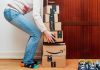 Person stacking Amazon boxes near door shoes nearby