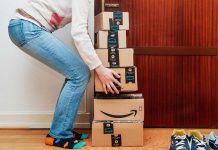 Person stacking Amazon boxes near door shoes nearby