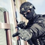 SWAT officer reaching for door handle.