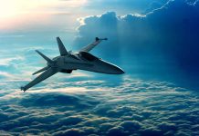 Jet flying above fluffy clouds at sunset