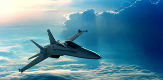 Jet flying above fluffy clouds at sunset