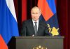 Man speaking at podium with flags behind him
