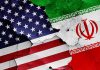 Cracked American and Iranian flags on concrete background