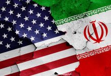 Cracked American and Iranian flags on concrete background