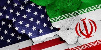 Cracked American and Iranian flags on concrete background