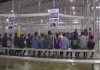 People sitting on benches inside a fenced facility