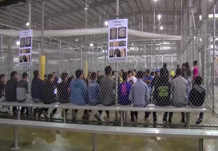 1229072206 featured image People sitting on benches inside a fenced facility