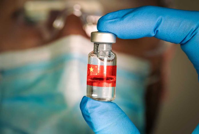 1873202461 featured image Gloved hand holding vial with red liquid and flag