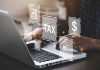 Person typing on laptop with tax-related icons displayed