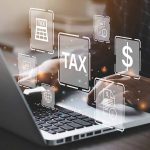 Person typing on laptop with tax-related icons displayed