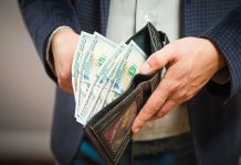 Person holding wallet full of hundred dollar bills