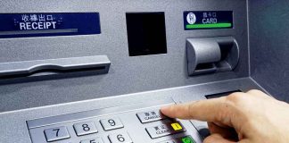 Person pressing button on an ATM keypad.