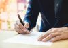 Person signing a document with a pen.