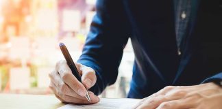 Person signing a document with a pen.