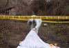 Crime scene investigator examining area with police tape