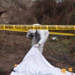 Crime scene investigator examining area with police tape