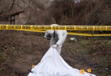 Crime scene investigator examining area with police tape