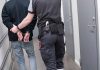 Officer escorting handcuffed person down hallway