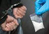 Handcuffed person with small bag of white marijuana