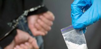 Handcuffed person with small bag of white marijuana