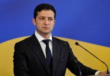 Man in suit speaking at podium with microphones