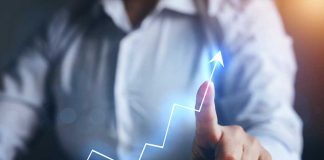 Person pointing at an upward trend line graph