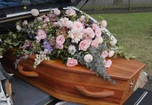 Coffin with flowers in the back of a hearse