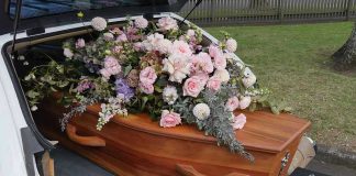 Coffin with flowers in the back of a hearse