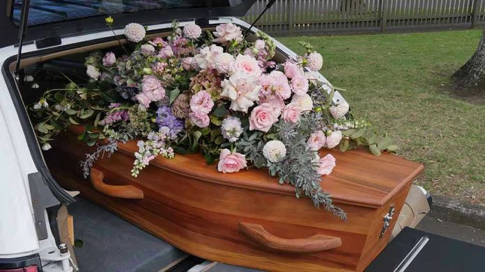 1929477455 Coffin with flowers in the back of a hearse