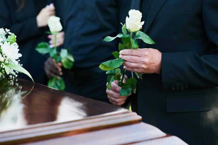 2360876145 Mourners holding white roses by a casket