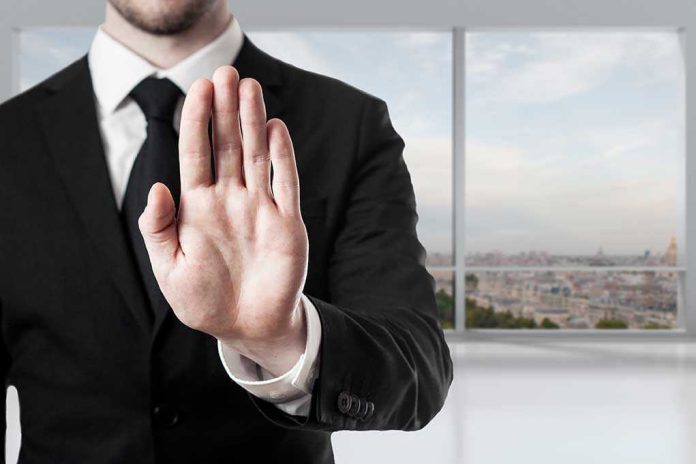 275001506 Person in suit with hand raised in stop gesture