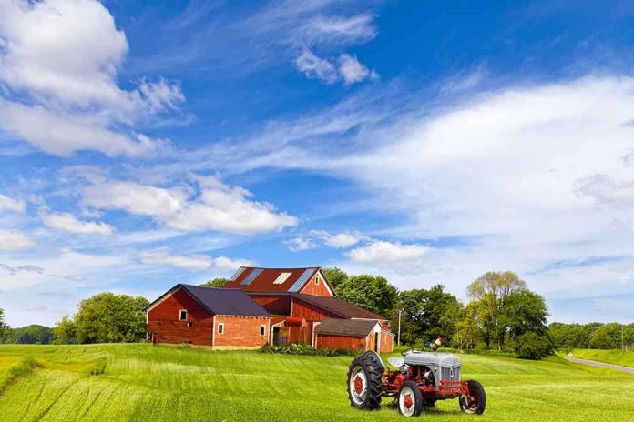 shutterstock_135351362.jpg A vintage tractor in front of a red barn on a sunny day