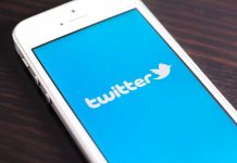 Close up of a smartphone displaying the Twitter logo on a blue background