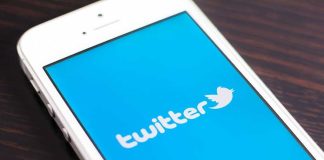 Close up of a smartphone displaying the Twitter logo on a blue background