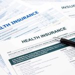 Close up of health insurance application forms with a pen