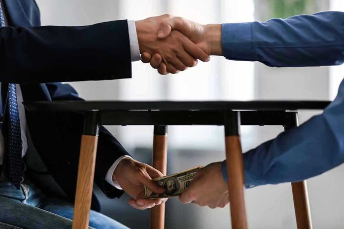 1225177960 Handshake and exchange of money under the table.