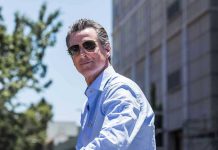 Man in sunglasses wearing a blue button-up shirt.